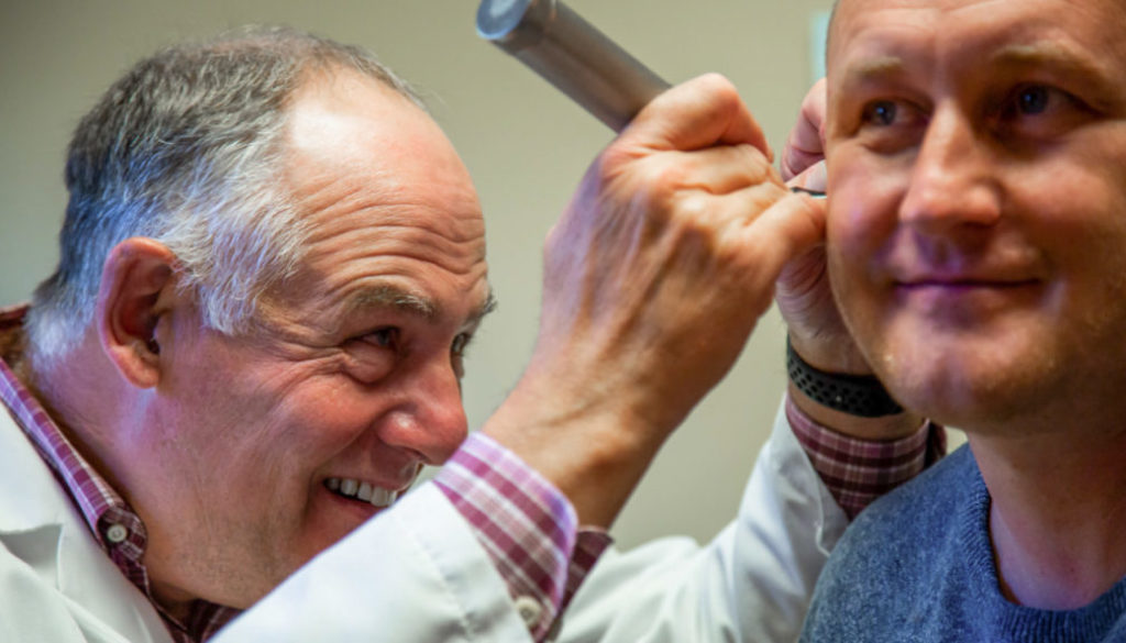 A physician inspects the inner ear of a male patient for a blog titled Why Men Over 30 Should Prioritize Their Annual Check-Ups by Richfield Medical Group