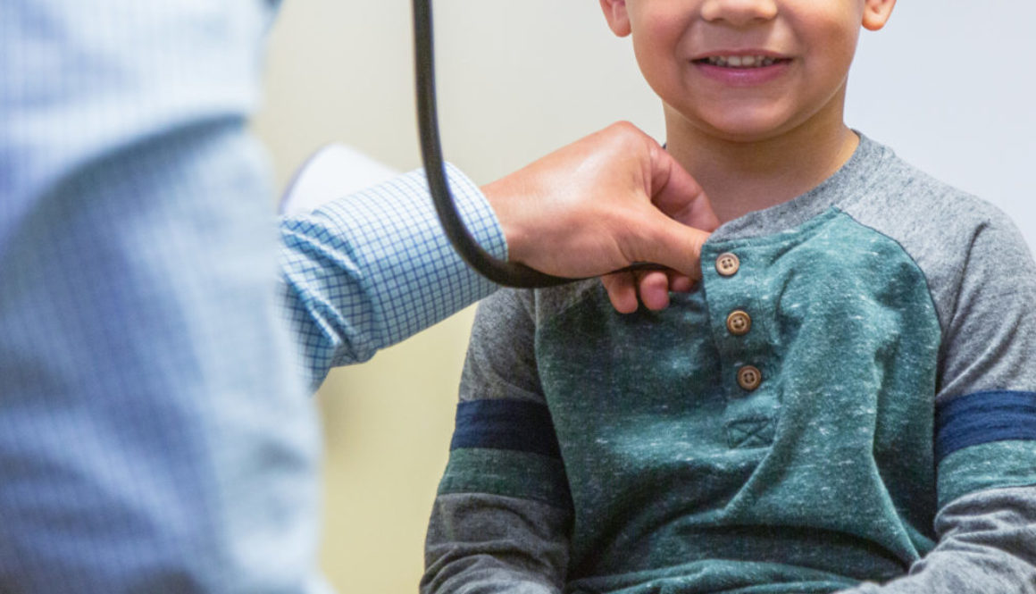 A doctor listens through a stethoscope to a child's breathing