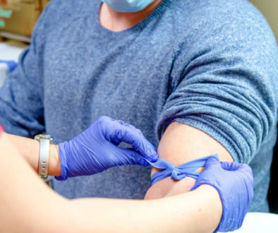 A nurse wraps a rubber band used for taking a blood sample.
