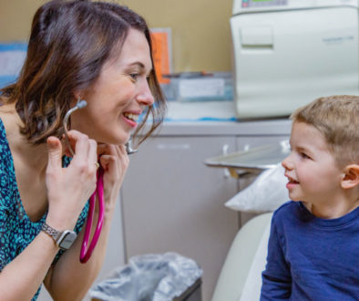 A Richfield Medical Group physician engages with a young patient, smiling as she puts on a stethoscope to listen to his heart.