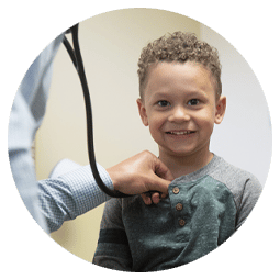 A smiling child gets a heart rate check by a Richfield Medical Group physician
